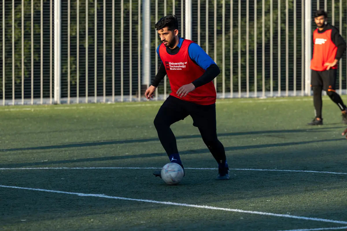 A student playing football on the UTB campus pitch.