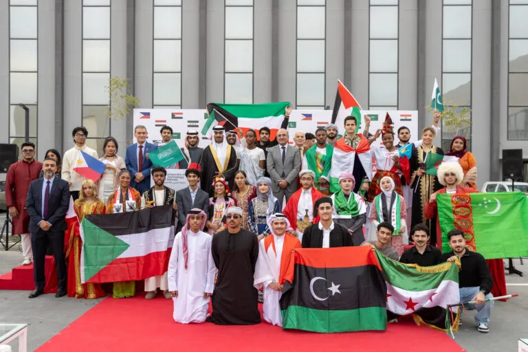 Students in national dress holding flags at UTB International Day.